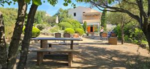 einen Picknicktisch in einem Park mit Bäumen und einem Gebäude in der Unterkunft Hotel Cala di l'Oru in LʼÎle-Rousse