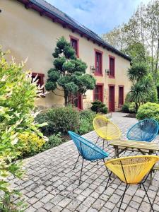 four chairs and a table in front of a house at Gite L'Etang in Miniac-sous-Bécherel