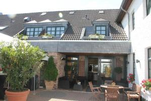 ein Gebäude mit einer Terrasse mit einem Tisch und Stühlen in der Unterkunft Hotel Rahserhof in Viersen