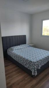 a bedroom with a bed with a blue comforter at Ap aconchegante em Sao Roque in São Roque