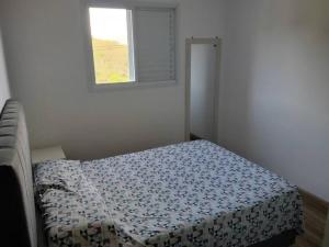 a bed in a room with a window at Ap aconchegante em Sao Roque in São Roque