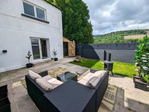 a patio with a couch and a table in a yard at Stylish House in Welsh Hills, Sleeps 8 to 12 in Rhondda
