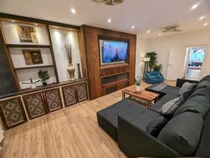 a living room with a black couch and a tv at Stylish House in Welsh Hills, Sleeps 8 to 12 in Rhondda