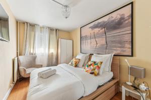 een slaapkamer met een groot wit bed en een stoel bij Chic and comfortable apart with balcony in Levallois-Perret