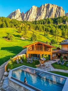 a house with a pool in front of a mountain at Kolfuschgerhof Mountain Resort in Colfosco