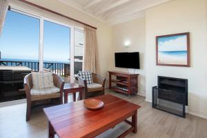 a living room with a fireplace and a television at Luxury Lodge at Pinnacle Point in Mossel Bay