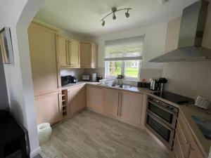 a large kitchen with wooden cabinets and a window at Gleneagles Rental in Auchterarder