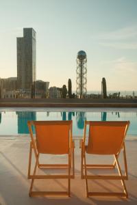 two chairs sitting next to a swimming pool at Rooms Hotel Batumi in Batumi