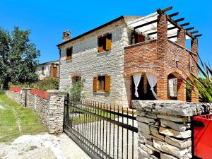 ein altes Backsteinhaus mit einem Zaun davor in der Unterkunft Villa Lena in Cabrunici Istria in Čabrunići