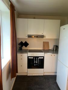 a small kitchen with a stove and white cabinets at Sentrums leilighet in Kabelvåg