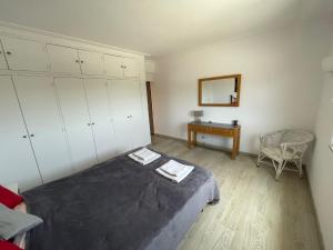 a bedroom with a bed and a mirror and a chair at Casa vista dos cerros in Loulé
