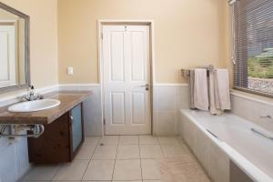 a white bathroom with a tub and a sink at Lifestyle Villa at Pinnacle in Mossel Bay +31 photos