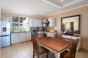a kitchen with a wooden table and a white refrigerator at Lifestyle Villa at Pinnacle in Mossel Bay