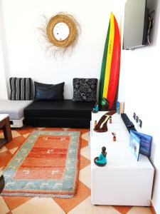 a living room with a black couch and a surfboard at Olas Surf House in Imsouane