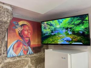 einen Flachbild-TV an der Wand mit einem Gemälde in der Unterkunft Casa Pereira in Balança