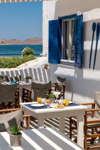 una mesa y sillas en un patio con el océano en el fondo en Naoussa Hotel Paros by Booking Kottas en Náousa