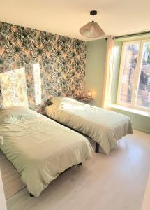 2 łóżka w sypialni z tapetą w kwiaty w obiekcie New appartement nature cœur de ville w mieście Avesnes-sur-Helpe