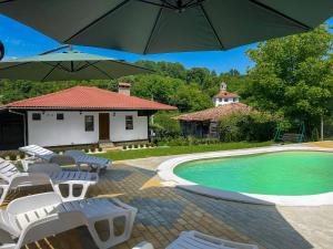 a pool with chairs and umbrellas next to a house at Старият Дюкянь in Elena
