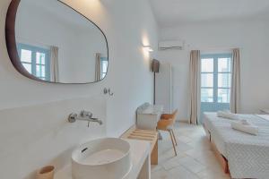 a white bathroom with a sink and a mirror at Hotel Mantalena in Antiparos Town