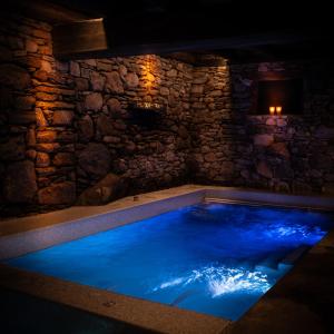 a large swimming pool in a stone walled room with a blue pool at Les Pardines 1819 Mountain suites & SPA in Encamp