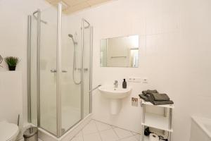 een witte badkamer met douche en wastafel bij Landküche - Ferienwohnung in Daun