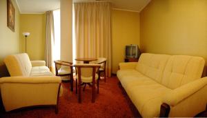 a hotel room with a couch and chairs and a table at Grot Hotel in Malbork