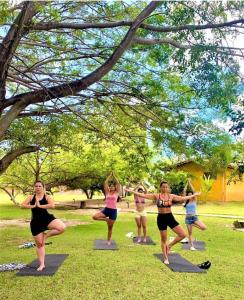 Angá Beach Hotel في ساو ميغيل دوس ميلاجريس: مجموعة من النساء لممارسة اليوجا في الحديقة