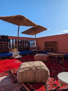 Habitación con mesas, sillas y sombrilla en Olas Surf House, en Imsouane