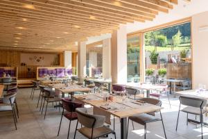 restauracja ze stołami i krzesłami oraz dużymi oknami w obiekcie Hotel Nevada w mieście Bormio