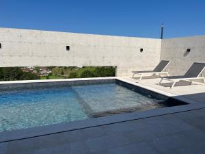 a swimming pool with two chairs next to a building at Vila Trnovac in Bužim
