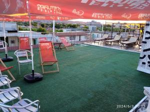 grupa krzeseł i stołów na patio z czerwonym parasolem w obiekcie Stupido Hotel Rimini w Rimini