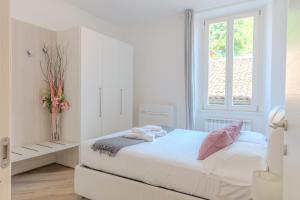 a white bedroom with a bed and a window at Appartamento Il Borgo in Bellagio