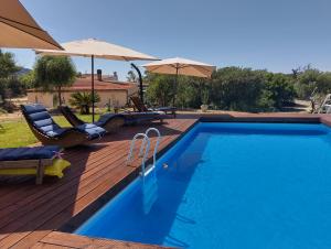a swimming pool with chairs and umbrellas on a wooden deck at Terra in Valledoria
