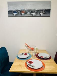 a wooden table with plates and glasses on it at Studio 3 personnes centre ville, avec cour in Calais +13 photos