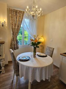 a dining room table with a vase of flowers on it at La Maison Chaleureuse in Ribérac +35 photos