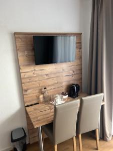 mesa con 2 sillas y TV en la pared en Hotel Casa Maria en Halblech-Buching