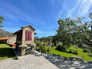 a stone building with a red door on a field at Casa d'Avó Lina - Gerês in Terras de Bouro