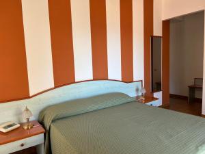 - une chambre avec un lit à rayures orange et blanche dans l'établissement Hotel Soleado, à Taormine