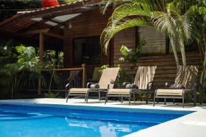 a pool with two lounge chairs next to a house at Casa Tulipan - Private 3bd, AC, Pool, Big Garden w' BBQ in Puerto Viejo