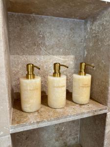 threeige bottles sitting on a shelf in a bathroom at Entre Ciel et Mer in Bonifacio