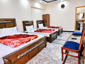 une chambre avec deux lits et une chaise dedans dans l'établissement New Palace Guest House, à Islamabad 12 autres photos