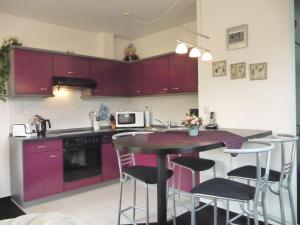 a kitchen with purple cabinets and a table with stools at NTST10002-FeWo-opn-Deep in Neue Tiefe Fehmarn