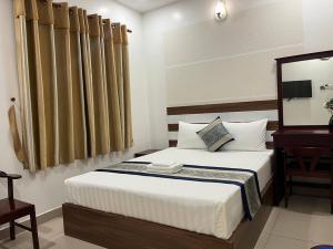 a bedroom with a bed and a table and a mirror at DINH DINH 2 AIRPORT HOTEL in Ho Chi Minh City