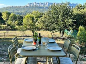 a picnic table with chairs and a bottle of wine at Maisonette Sainte Victoire in Fuveau