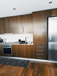a kitchen with wooden cabinets and a stainless steel refrigerator at Gerês VillaCella in Vieira do Minho