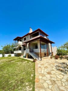 a house with a porch and a green lawn at Elia - Seaside Home in Nea Potidaea