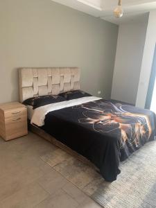 a bedroom with a bed and a wooden nightstand at Bel appartement à Harhoura in Oulad Kerroum +13 photos