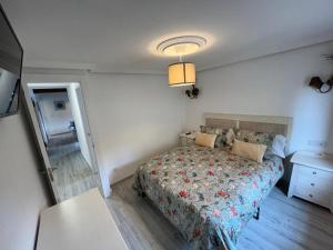 a bedroom with a bed with a floral bedspread at Apartamentos BuenaVista in Colunga