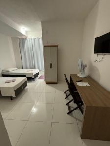 a room with two beds and a desk with chairs at Shalom Flat Hotel in Pará de Minas