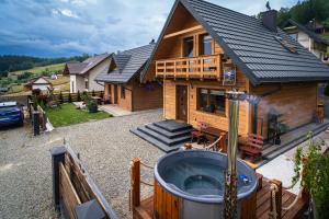 a house with a hot tub in front of it at Apartament z widokiem na Jezioro Solińskie - Zawóz in Zawóz +6 photos